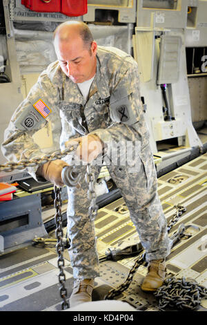 U.S. Army Sgt. Bradford Caldwell, a 19K, M1 Armor Crewman, secures a M1A1SA Abram using heavy-duty chains aboard a C-17 prior to flight. The South Carolina Army National Guard’s 1-118th Combined Arms Battalion (CAB) participates in heavy airlift operations April 10-11, 2014 at Wright Army Airfield (WAAF), Hinesville, Ga., to demonstrate the joint, total force, capabilities of the S.C. Army Guard and U.S. Air Force Reserve’s 315th Airlift Wing.  Soldiers and Airmen worked in unison over two days to load and secure four of the 1-118th CAB’s new M1A1SA Abrams Main Battle Tanks onto four U.S. Air  Stock Photo