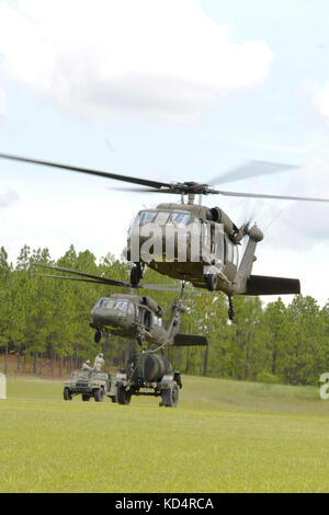 U.S. Army Soldiers with the 351st Aviation Support Battalion, S.C. Army National Guard, hook up a humvee and water buffalo to Black Hawks to practice sling load operations at Fort Jackson, July 13, 2014.  The training is part of the unit’s pre mobilization preparedness for their upcoming deployment to Kuwait. (U.S. Army National Guard photo by Sgt. Brian Calhoun/Released) Stock Photo
