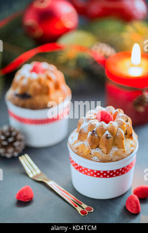 Mini Bundt Cherry Cakes sprinkled with Powdered Sugar, Candles, Christmas Tree and Tea on Black Table Stock Photo