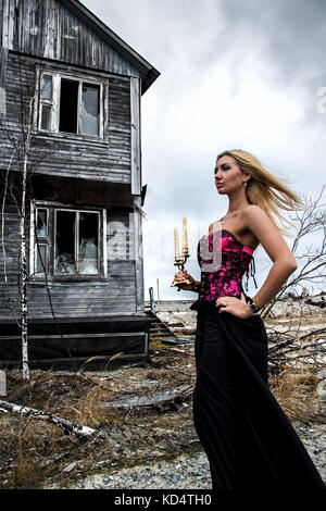 Beautiful young woman with candles at the background of the old wooden house Stock Photo