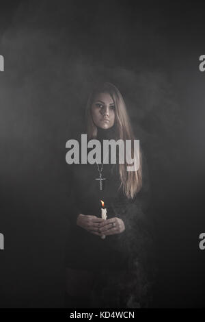 Lonely young woman holding a candle in a smoke Stock Photo