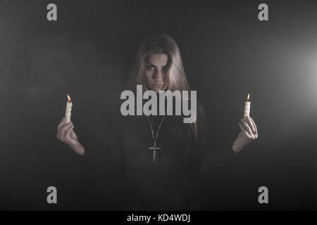 Lonely young woman holding two candles in a smoke Stock Photo