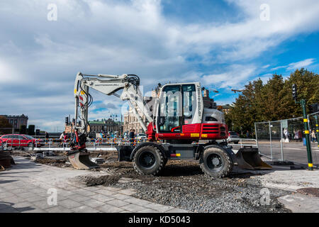 Stockholm, Sweden- October 5, 2017: Red and white excavator in an fenced of part of the street. People in the background Stock Photo