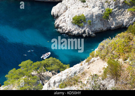 Calanque de Sugiton, boat in an inlet, people swimming in azure sea water, Calanques National Park, France Stock Photo