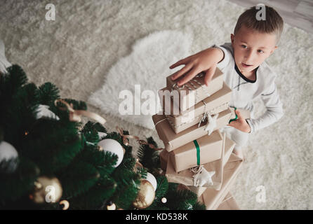 Boy arranging  stack of christmas presents Stock Photo