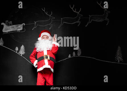 Child in santa claus costume pointing at background Stock Photo