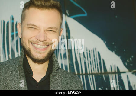 positive smiling man on the background of a painted wall. toned. Stock Photo