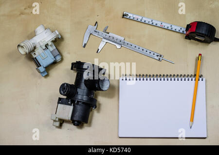 Materials, accessory and spare parts for hydraulics. Notes and measuring tools on the workshop table. Wooden table. Stock Photo