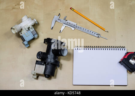 Materials, accessory and spare parts for hydraulics. Notes and measuring tools on the workshop table. Wooden table. Stock Photo