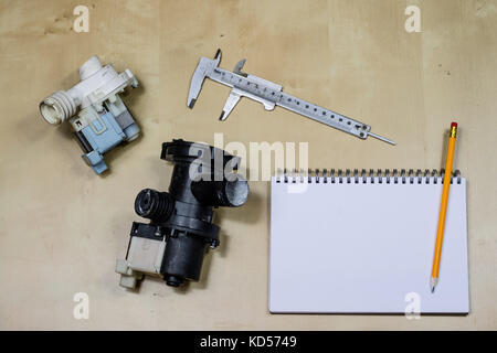 Materials, accessory and spare parts for hydraulics. Notes and measuring tools on the workshop table. Wooden table. Stock Photo