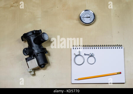 Materials, accessory and spare parts for hydraulics. Notes and measuring tools on the workshop table. Wooden table. Stock Photo