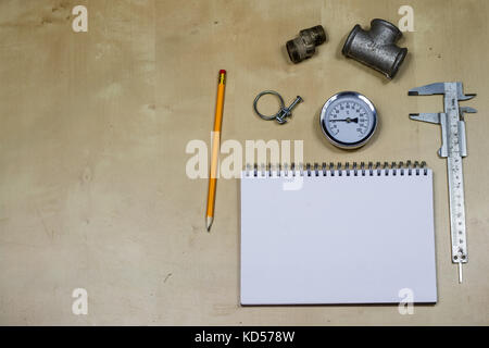 Materials, accessory and spare parts for hydraulics. Notes and measuring tools on the workshop table. Wooden table. Stock Photo