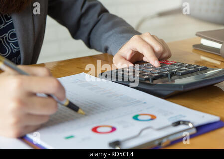 Business and finance concept of office working, Businesswoman using calculator to calculate and discussing analysis chart Stock Photo