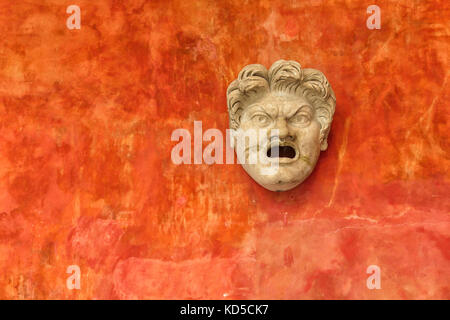 Stone face of angry man against a bright orange wall. Ancient Roman head in museum Glyptotek in Copenhagen, Denmark Stock Photo