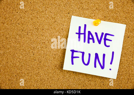 A yellow sticky note writing, caption, inscription Have fun in black ext on a sticky note pinned to a cork notice board Stock Photo