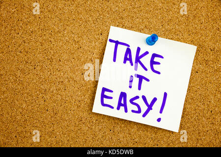 A yellow sticky note writing, caption, inscription take it easy, motivational lifestyle reminders against black ext on a colorful sticky note pinned to a cork notice board Stock Photo