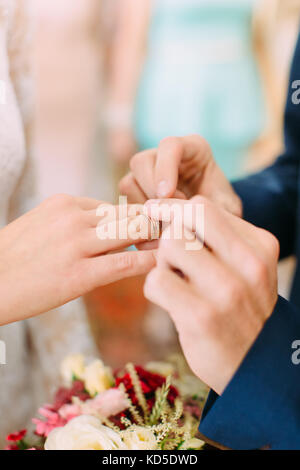 Close-up view of the hands of groom putting the wedding ring on the finger of bride. Stock Photo