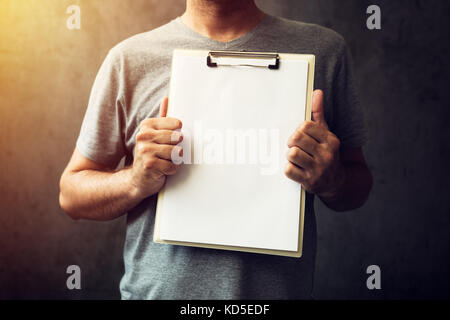 Casual caucasian adult man holding blank notepad paper as copy space Stock Photo
