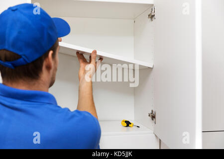 furniture assembly - worker installing cabinet shelf Stock Photo