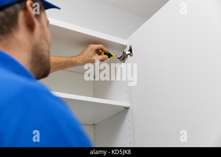 furniture assembly service - worker installing cabinet doors Stock Photo