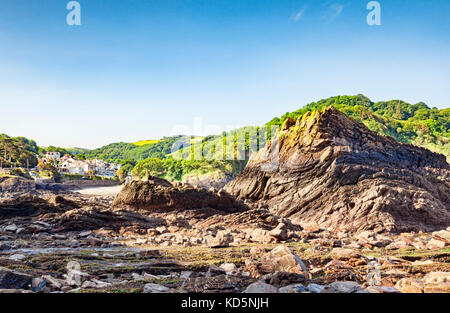 The rocky beach at Combe Martin, North Devon, England, UK, with the village in the background. Stock Photo