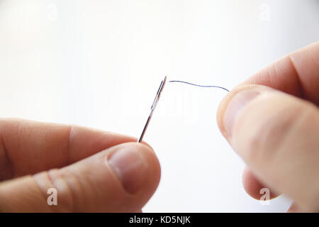 Caucasian hands threading the needle preparing to sewing. Empty copy space for Editor's text. Stock Photo