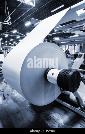unwinding a roll of paper in a modern printing house Stock Photo