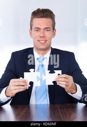 Close up of hands connecting puzzle element and making jigsaw complete ...