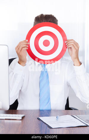 Businessman Holding Dartboard In Front Of Face Stock Photo