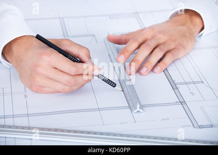 Close-up Of Male Architect Working On Blueprint At Desk Stock Photo