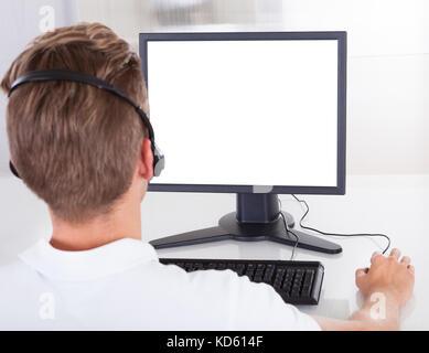 Rear View Of Young Man With Headphone Using Computer Stock Photo
