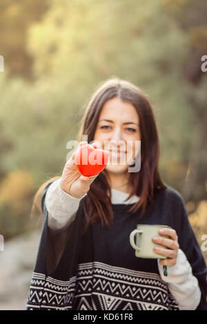 Portrait of beautiful young woman holding red heart against of forest Stock Photo