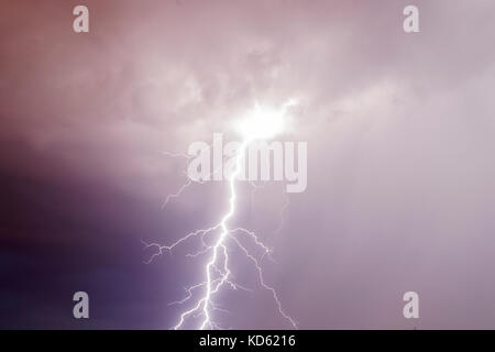 Thunder storm lightning strike on the dark purple cloudy sky background at night Stock Photo