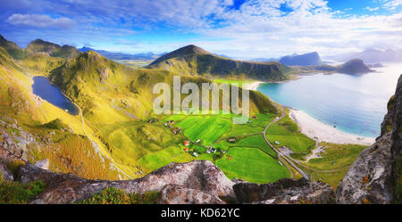 Sunny autumn day in Norway. Green valleys and mountain lake in sunlight. Lofoten landscape view from rock peak. Stock Photo