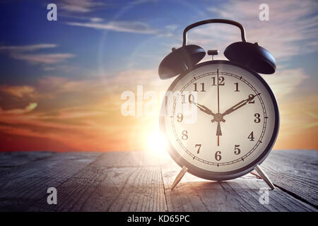 Alarm clock on wood table at sunset Stock Photo