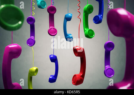 Red and multi-coloured telephone receiver hanging over gray background concept for on the phone, customer service, on hold or contact us Stock Photo