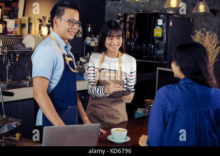 Young asian baristas ordering at counter bar in cafe. Cafe restaurant service, food and drink industry concept. Stock Photo