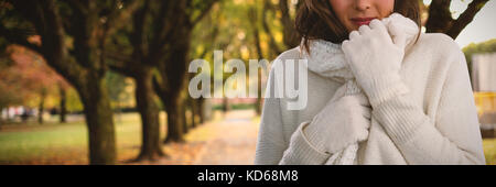Portrait of young woman in warm clothing against footpath amidst trees at park Stock Photo