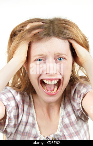 Young woman screaming in agony with mouth wide open holding head Stock Photo