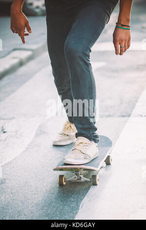 Skateboarder legs riding skateboard on the street. Close up Stock Photo