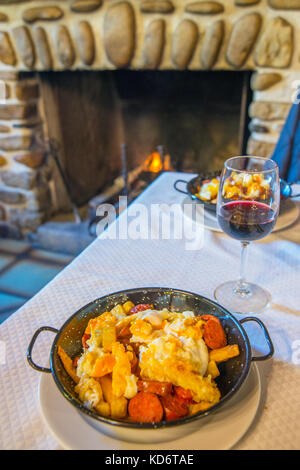 Fried eggs with potatoes and chorizo in a restaurant. Rascafria, Madrid province, Spain. Stock Photo