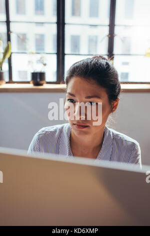 Close up of a businesswoman working on computer at her office desk. Young professional working on computer. Stock Photo