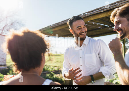 Young people having a party in garden restaurant. Group of multi-ethnic friends enjoying party on a sunny day. Stock Photo