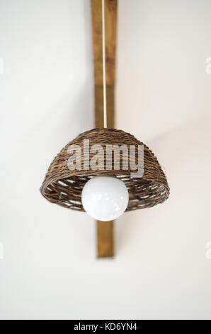 Hand made wicker woven basket diy lifestyle lamp with large white led globe, cable, hanging from old wood beam Stock Photo