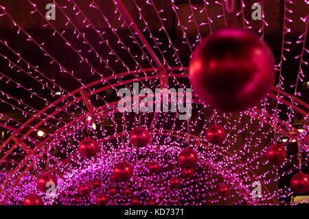 Colorful Xmas decoration of many LED light. Decorative Christmas red balls hang out on the outdoor decoration of the construction. Stock Photo