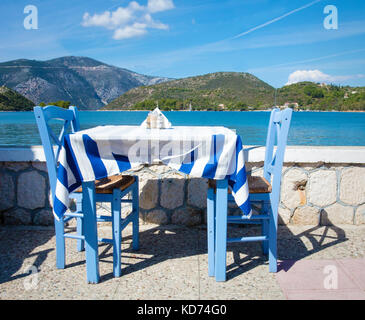 Blue table with two chairs plus Greek flag tablecloth in a restaurant by the sea in Vathy the capital of Ithaca in the Ionian Islands Greece Stock Photo