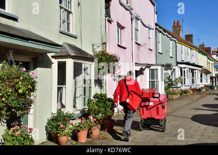 Postman on rounds in row of terrace houses on high street in small English market town of Thornbury, South Gloucestershire Stock Photo