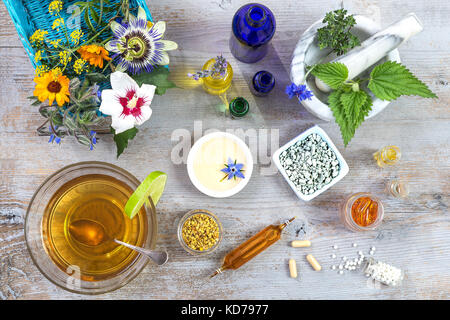 Ceramic mortar with herbs and fresh medicinal plants on old white wooden tboard. Preparing medicinal plants for phytotherapyand health beauty Stock Photo