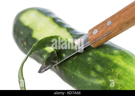 Cucumber being peeled with a wooden peeler and a Bark from peeled cucumber on white Stock Photo