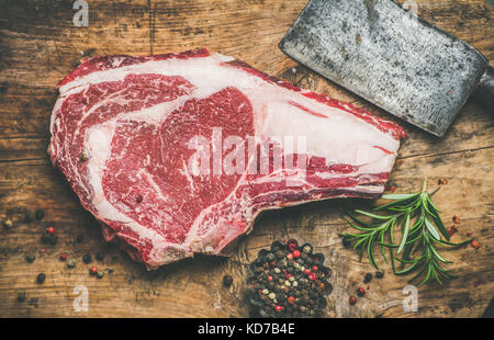 Raw beef steak rib-eye with seasoning and knife, rustic background Stock Photo